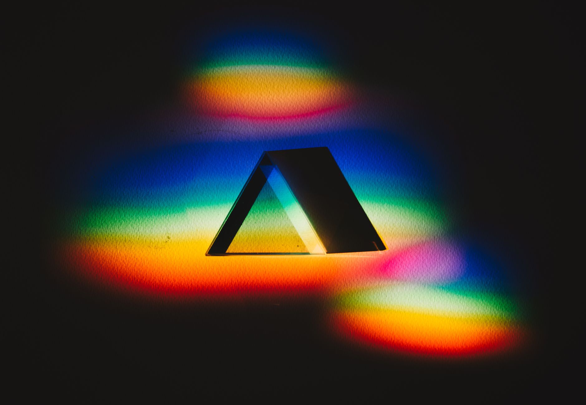 Colorful dispersion of light through a prism creating a vibrant rainbow spectrum on a dark background.