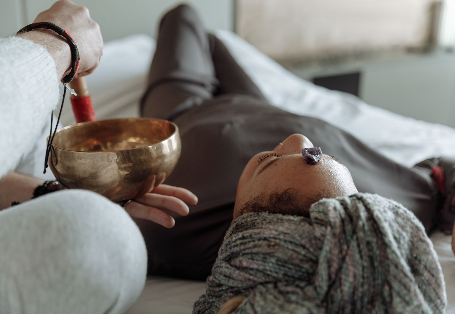 A serene relaxation therapy session with a Tibetan singing bowl and crystal on forehead, promoting spiritual healing.