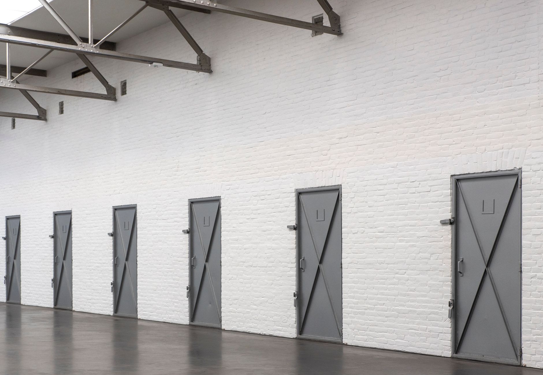Spacious industrial warehouse showing metal doors on a white brick wall.