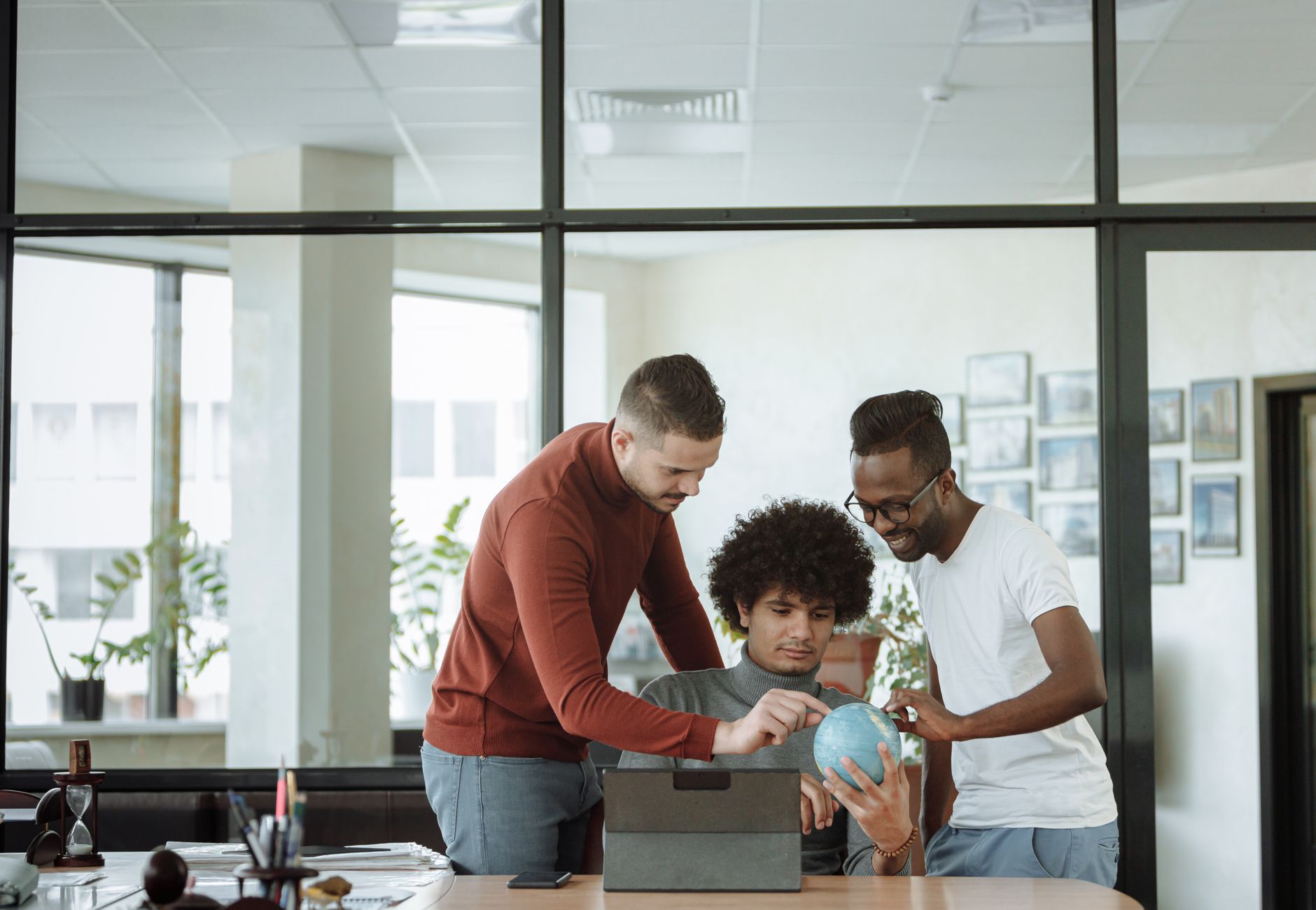 Young professionals gathered around a desk, discussing ideas with a globe, symbolizing global collaboration.