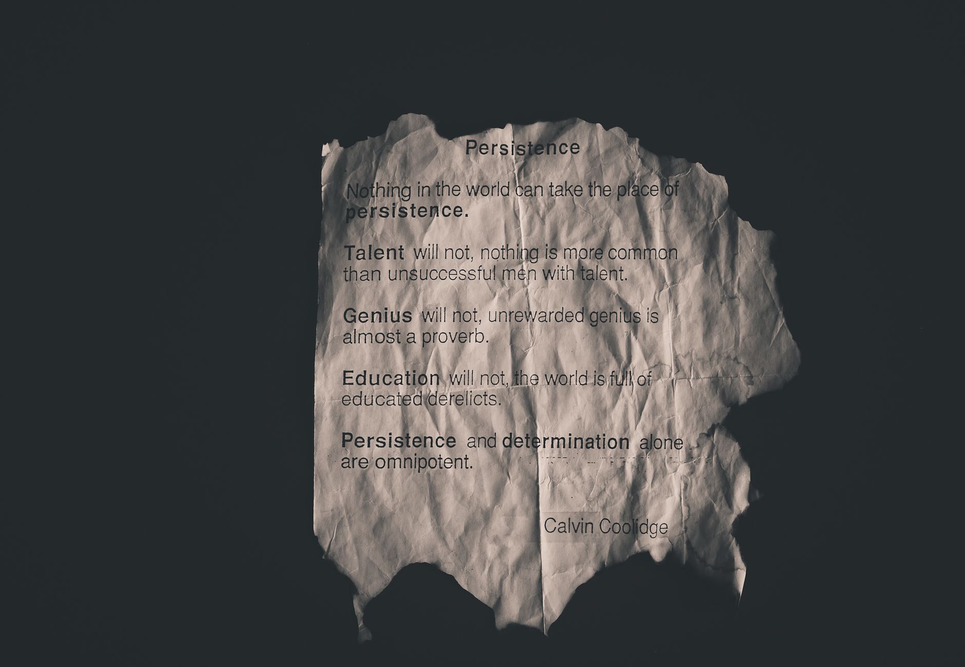 Calvin Coolidge quote on perseverance printed on crumpled paper.