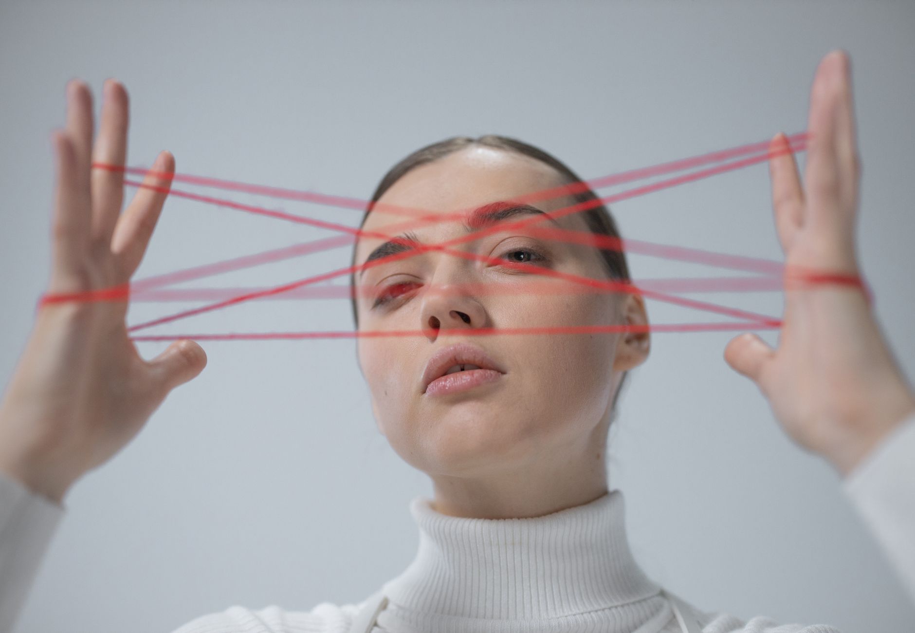 Creative portrait of a woman interacting with a red string art concept.