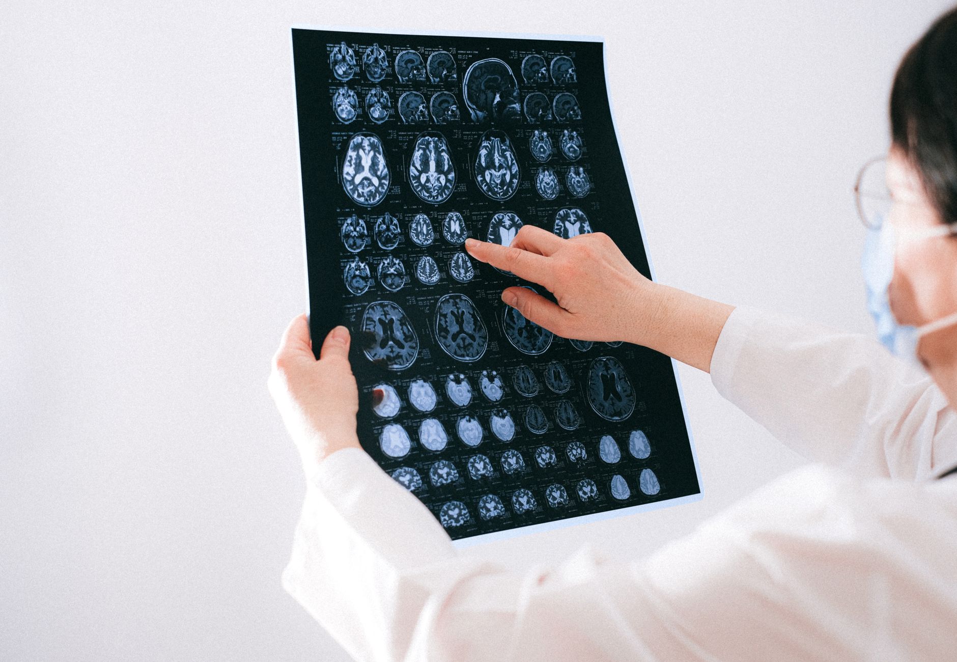 Doctor examines brain MRI scans closely for medical diagnosis in a hospital environment.