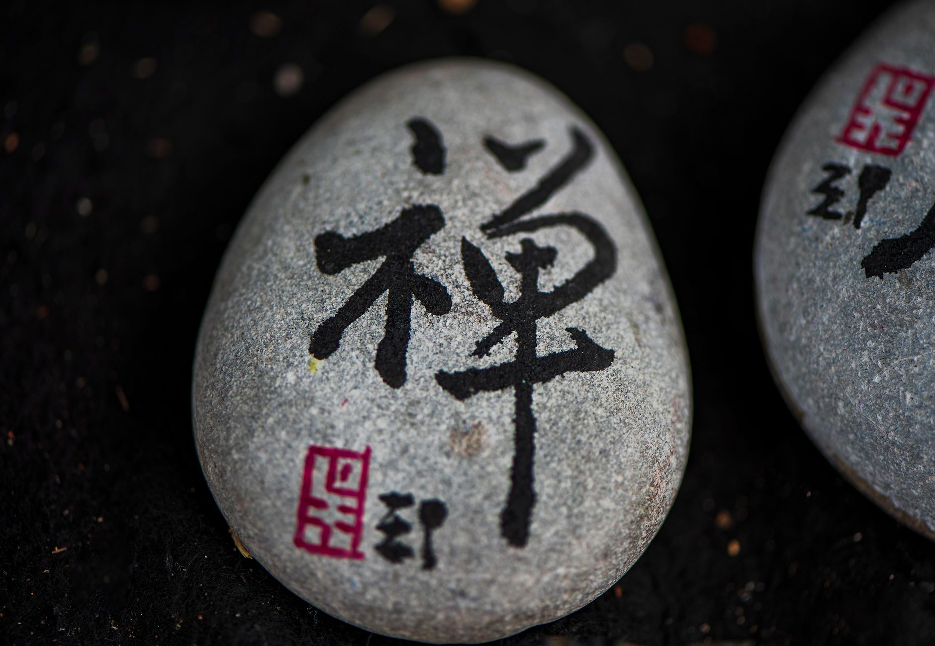 Close-up of a stone with Japanese calligraphy symbolizing zen and tranquility.